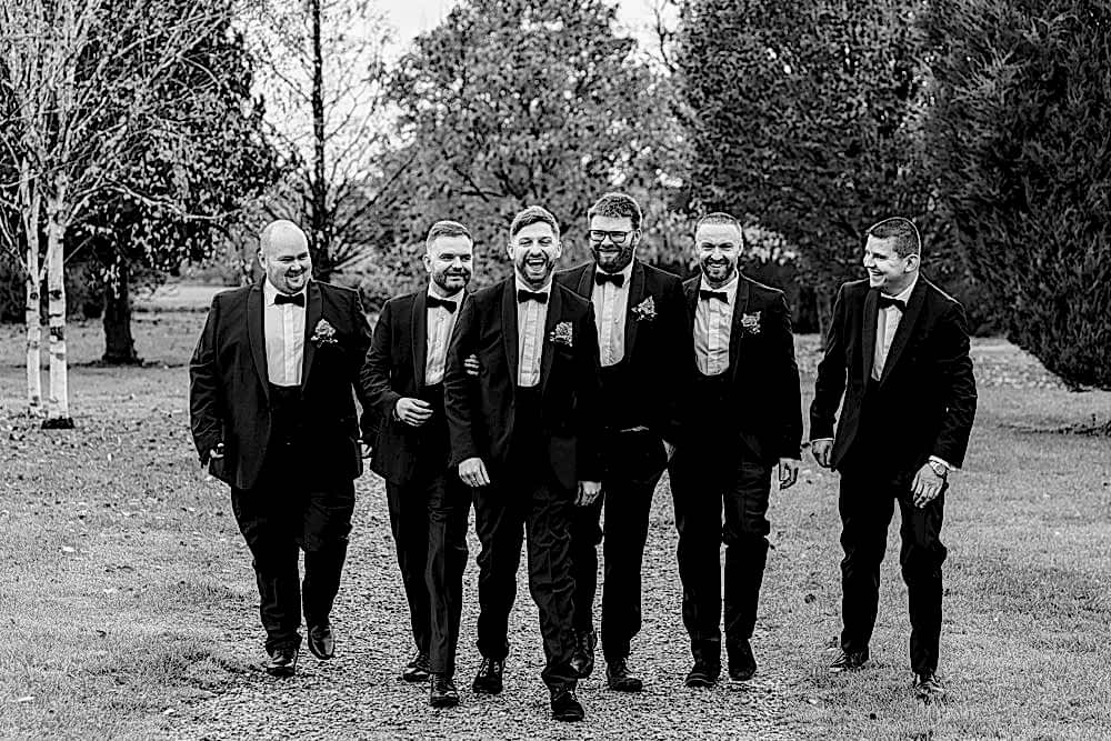 Group of men in suits laughing outdoors.