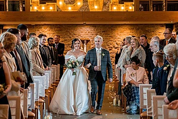 Bride walking down aisle with father, wedding ceremony.
