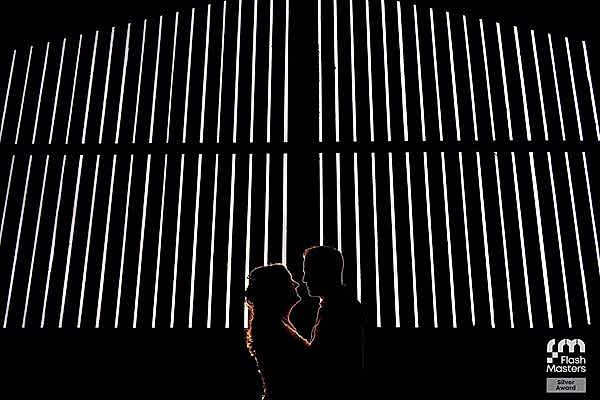 Couple silhouette against illuminated stripes background.