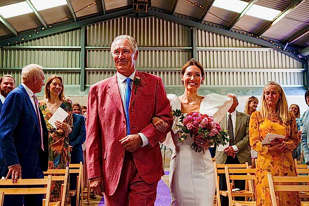 Bride walking down aisle with father at wedding ceremony.