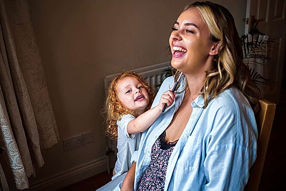 Laughing woman with playful girl at home.