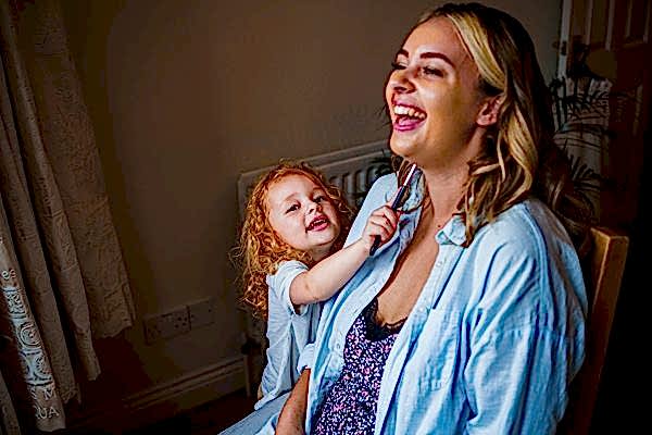 Mother and child laughing together indoors.