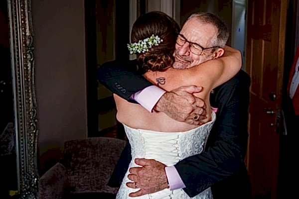 Bride and father embracing on wedding day.