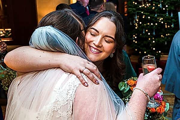 Bride embracing guest at festive wedding reception.