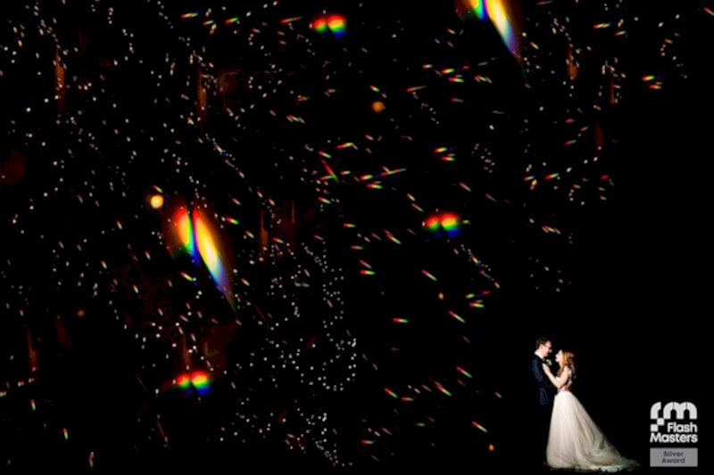 Couple embracing amidst sparkling lights at night.