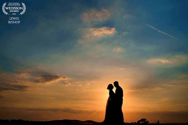 Couple silhouetted against sunset, award-winning wedding photo.