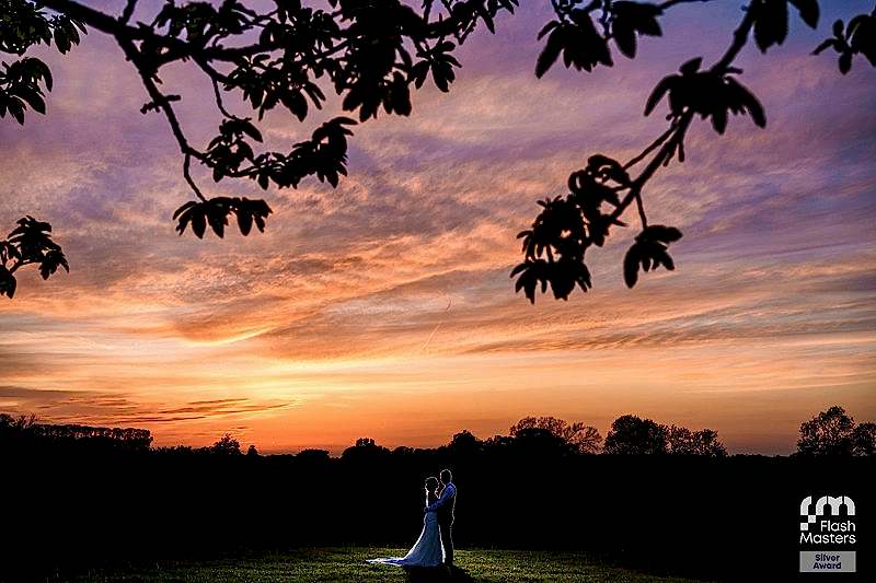 Couple silhouetted against vibrant sunset sky.