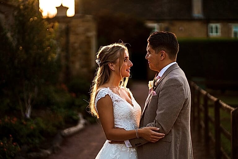 Couple in wedding attire during sunset ceremony.