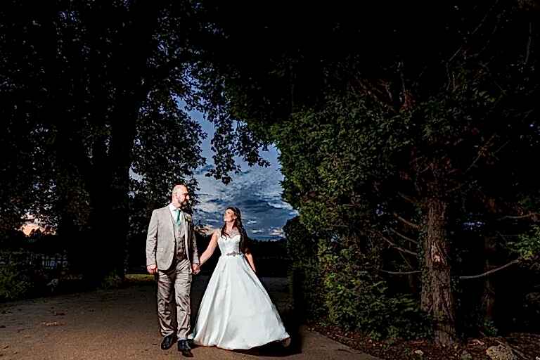 Bride and groom walking at dusk, countryside wedding.