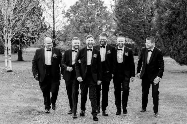 Group of men in suits laughing outdoors.