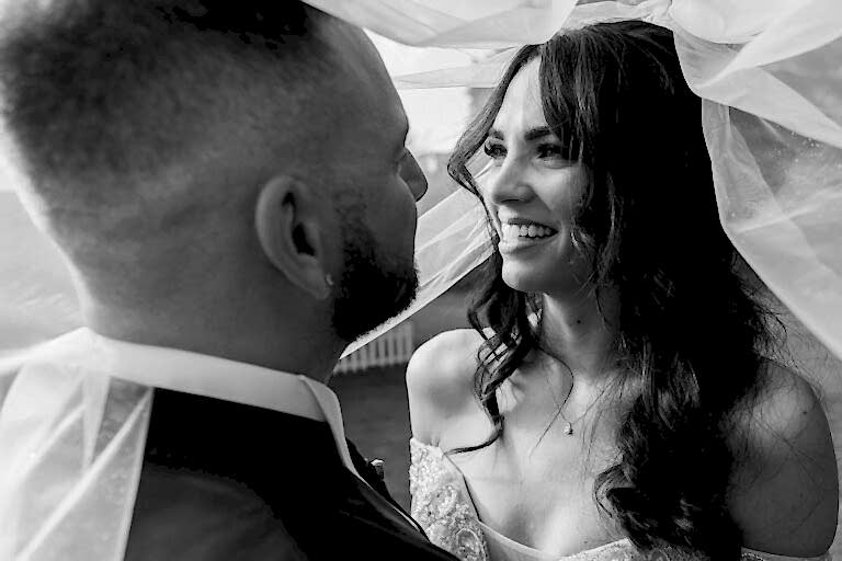 Couple sharing intimate moment under bridal veil.
