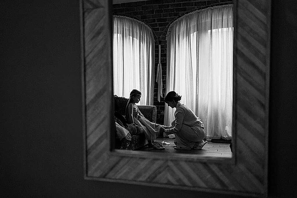 Reflection of a woman helping a girl with shoes.