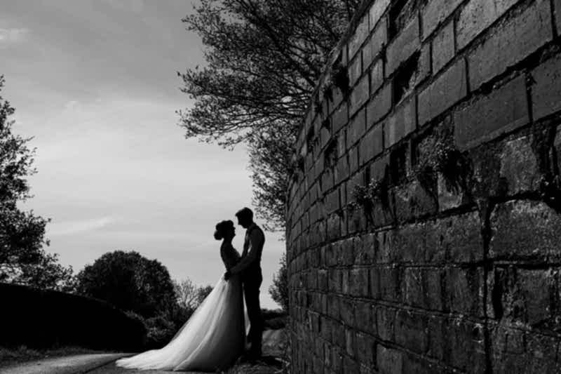 Bride and groom silhouetted against a wall.