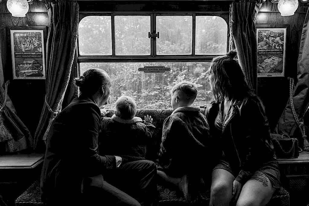 Family in a train carriage, looking out the window.