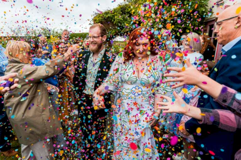 Couple surrounded by colourful confetti celebration.