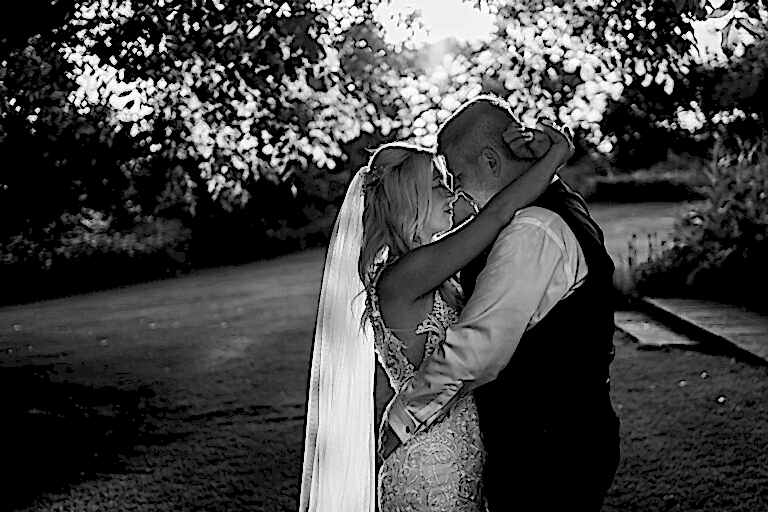 Bride and groom embracing in garden
