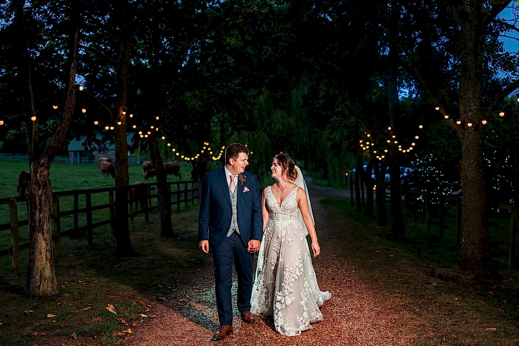 Bride and groom walking under fairy lights.