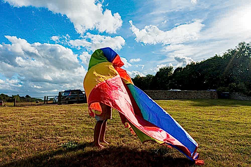 Child playing with colourful kite in sunny field.