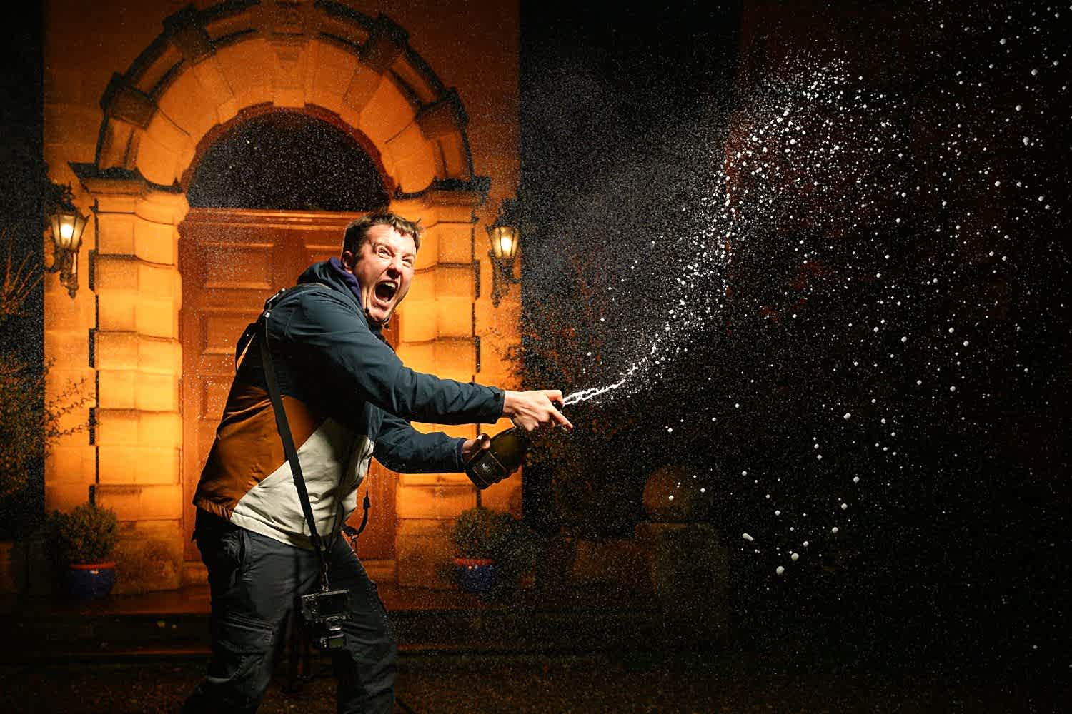 Man celebrating with champagne spray outside building