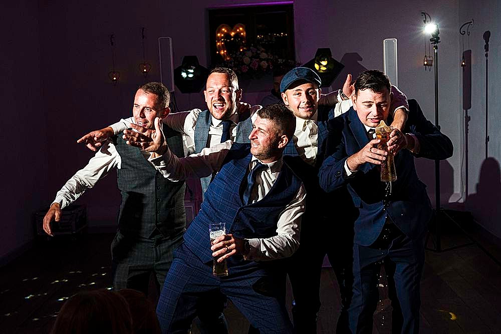 Five men in suits laughing and having fun