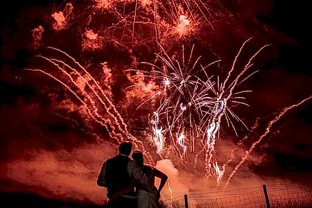 Couple watching fireworks lighting up night sky.