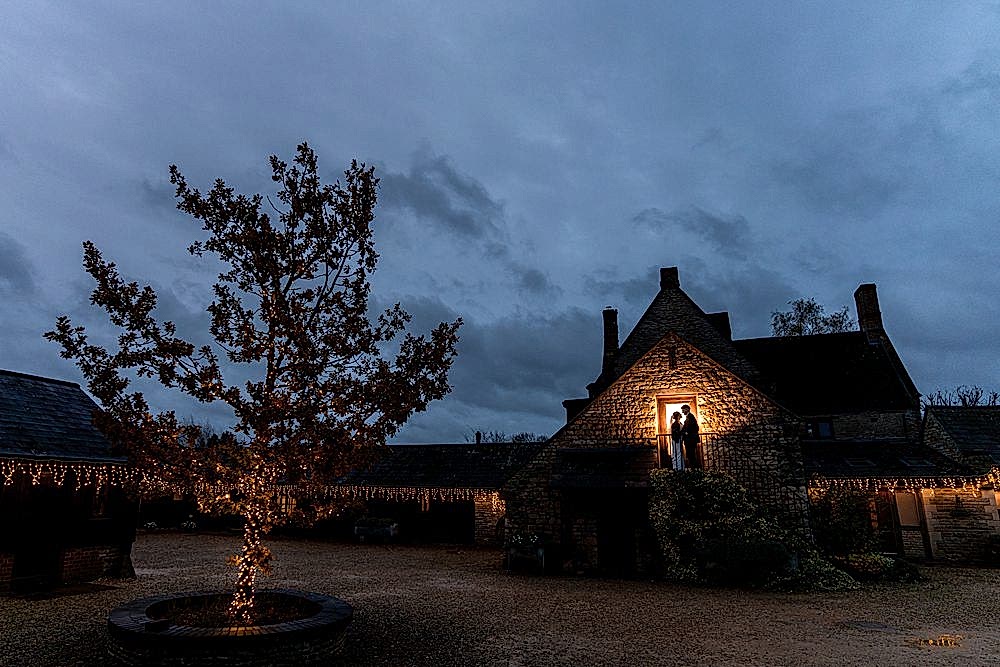 Silhouetted couple in doorway, fairy lights on tree.