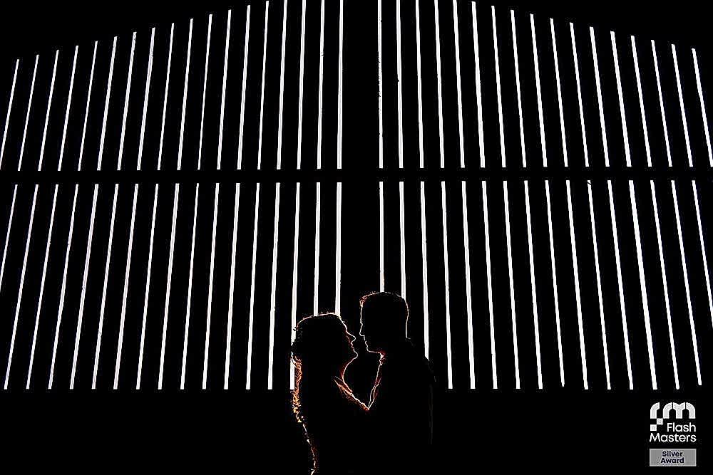 Silhouette of couple against striped lights in darkness.