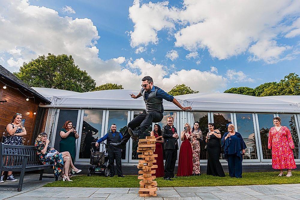 Man balancing on giant Jenga at outdoor event.