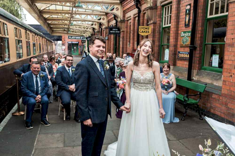 Couple marries at vintage train station with guests seated.