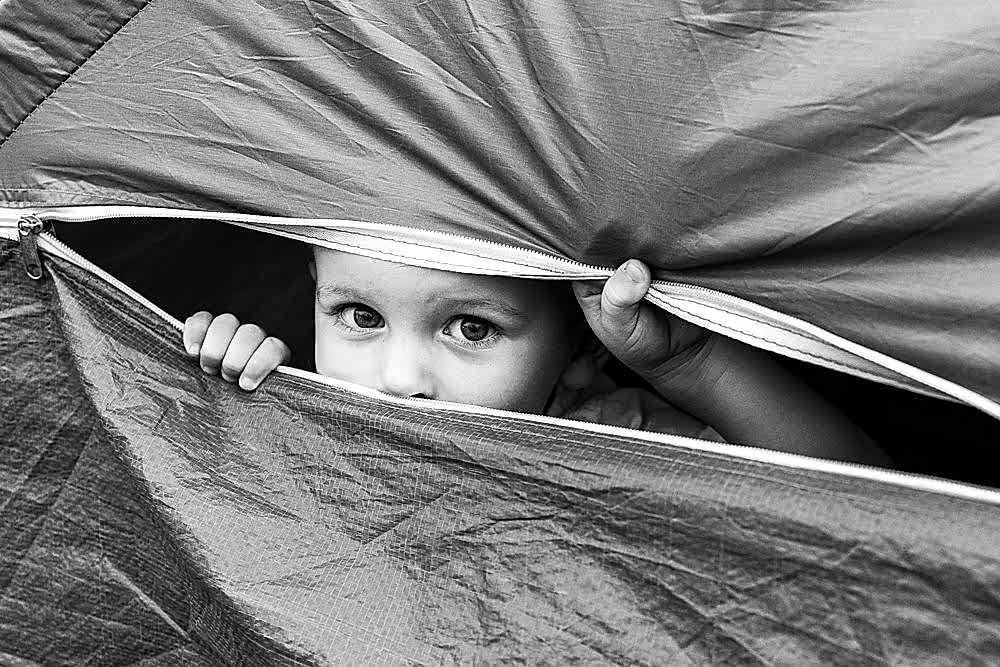 Child peeking through tent flap