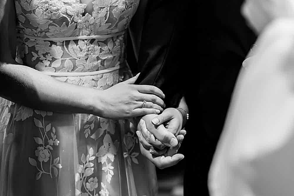 Bride and groom holding hands at wedding ceremony.