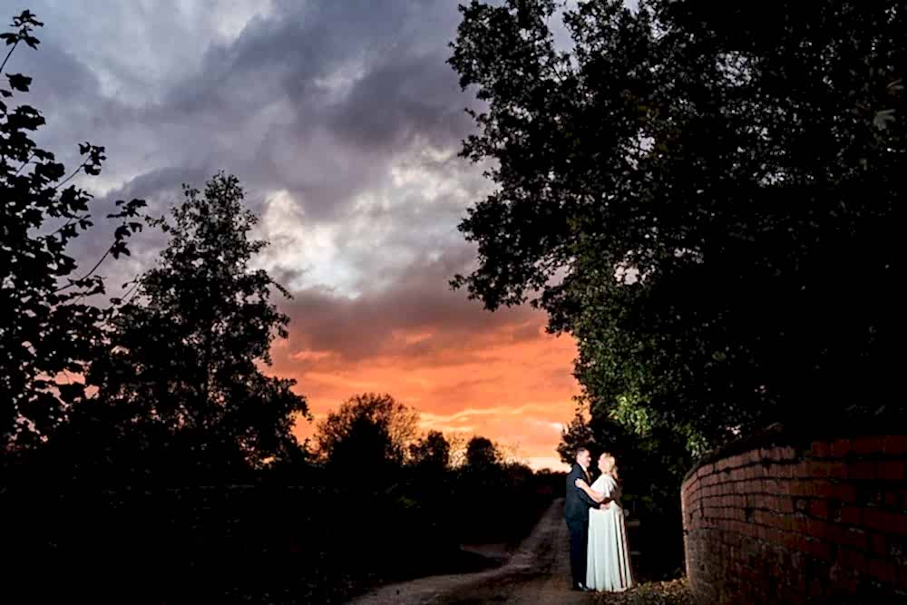 Couple embracing under vibrant sunset sky.