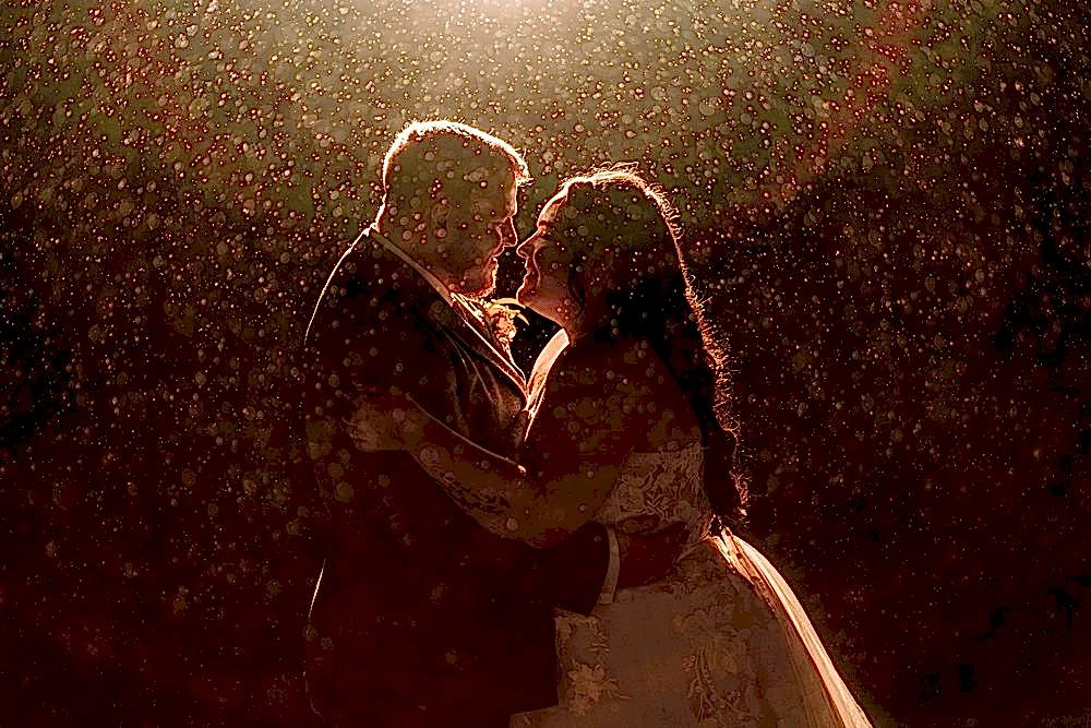 Romantic couple embraces under golden rain at night.