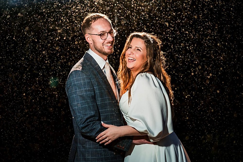 Smiling couple embracing in the rain at night.