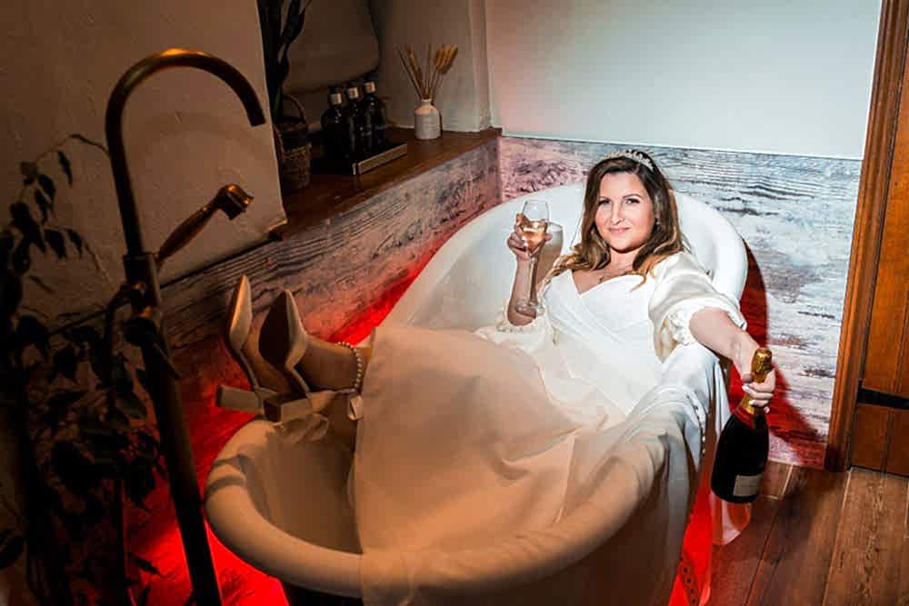 Bride relaxing with champagne in the bathtub.