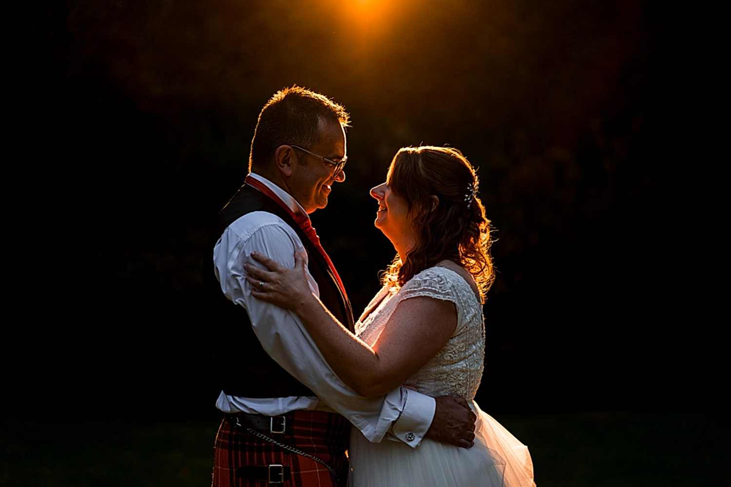 Couple embraces in warm sunset glow.