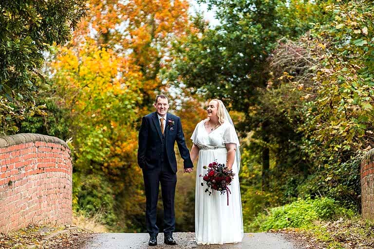 Bride and groom on autumnal bridge.