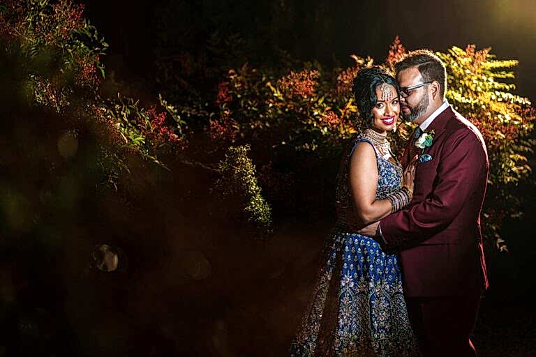 Couple in colourful attire embracing outdoors at night.