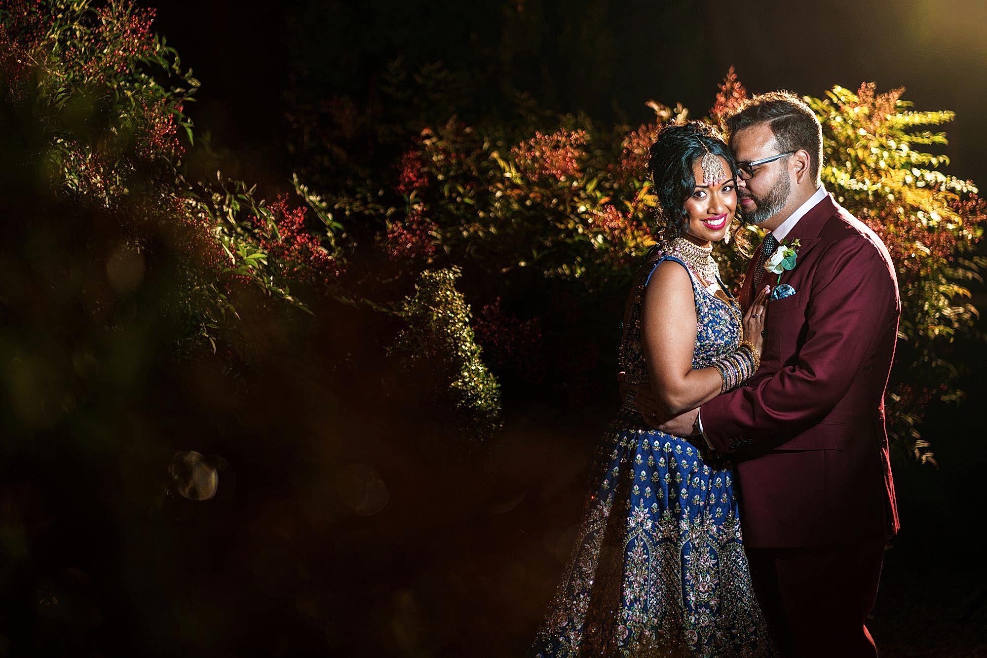 Couple in colourful attire embracing outdoors at night.