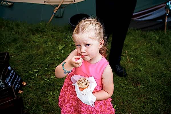 Young girl eating ice cream at outdoor event.