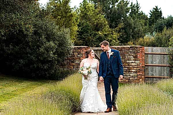 Bride and groom walking in garden path.