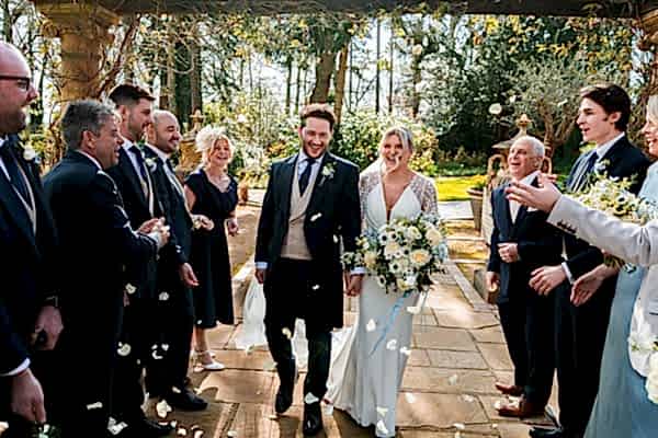 Bride and groom celebrate with guests outdoors.