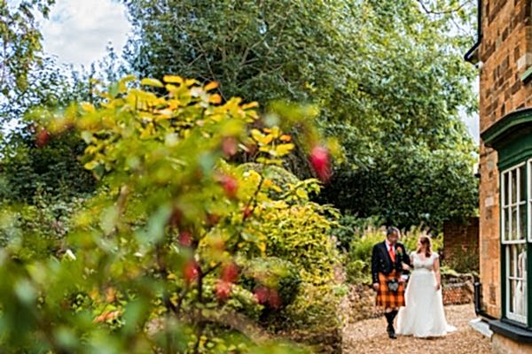 Couple in garden wedding attire walking together joyfully.