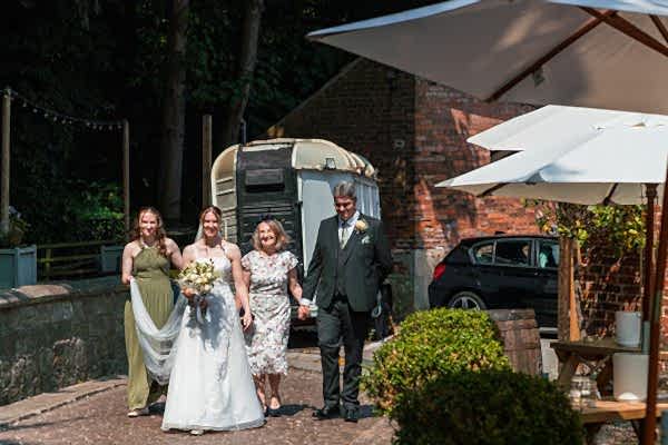 Wedding procession under sunlight, outdoor venue.