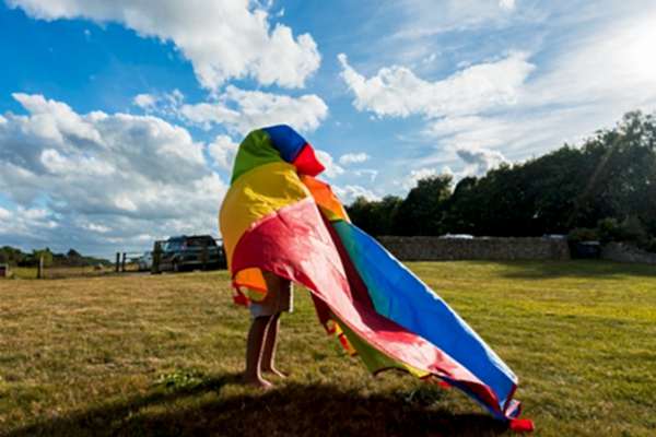 Child playing with colourful parachute outdoors.