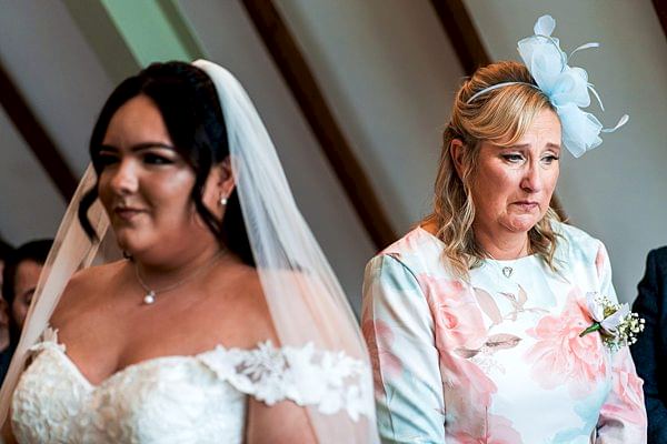 Bride and emotional woman at wedding ceremony.
