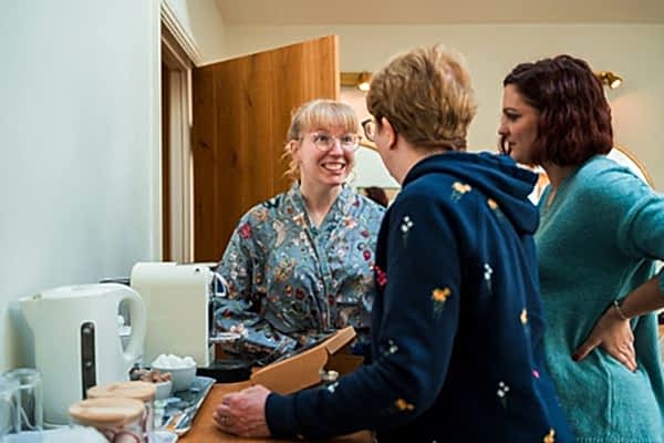 People chatting by a kettle in kitchen.