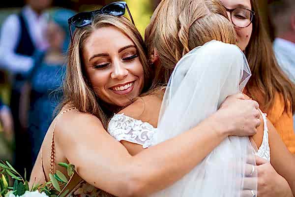 Bride hugs friend at wedding celebration.