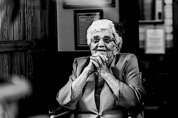 Elderly woman smiling in monochrome portrait.