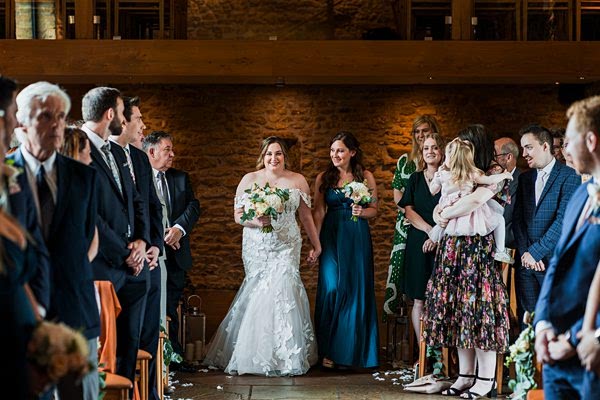 Bride and bridesmaid walking down the aisle, smiling.